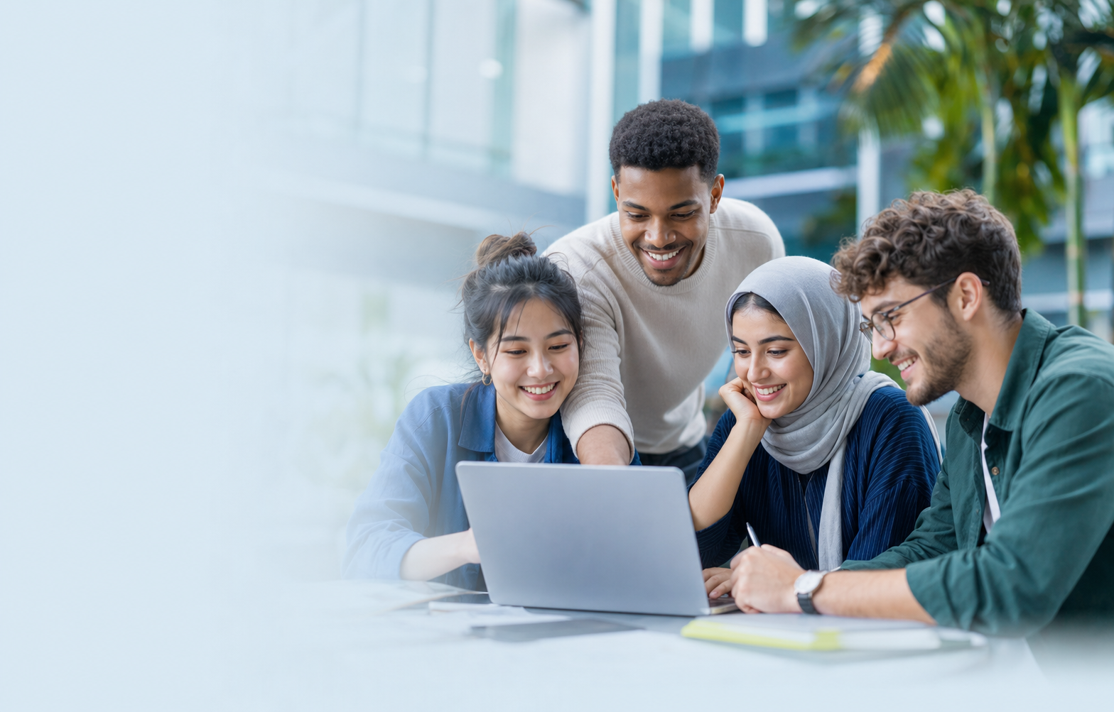Four international students collaborating around a laptop